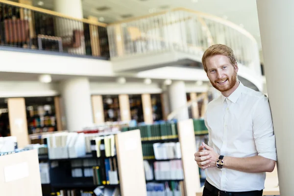 Handsome student smiling in library — Stock Photo, Image