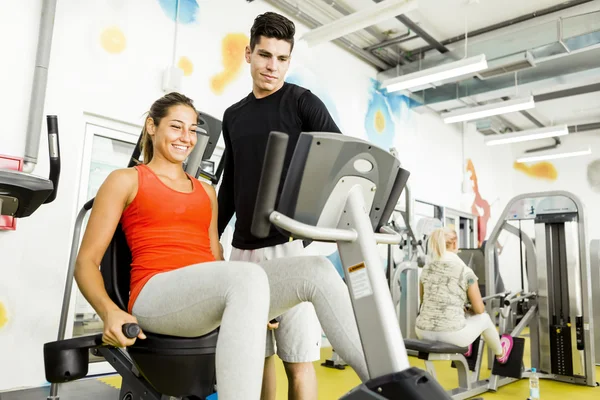 Beautiful woman instructed by a man in a gym — Stock Photo, Image