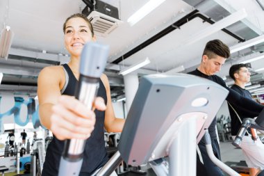 Eliptik bir eğitmen kullanan kadın genç yerleştirmek