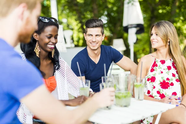 Happy friends sitting talking at a table — Stock Photo, Image