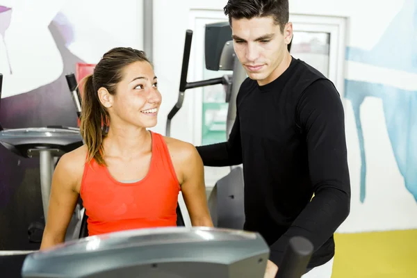 Beautiful woman instructed by a man in a gym — Stock Photo, Image