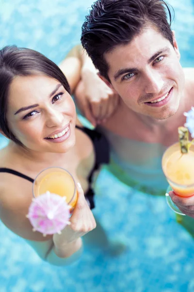 Pareja bebiendo un cóctel en una piscina — Foto de Stock