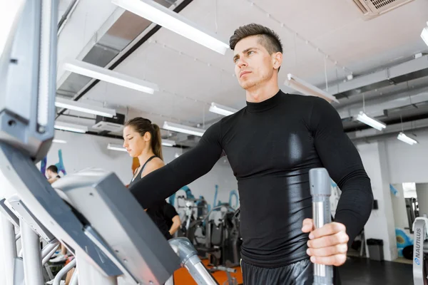 Grupo de personas trabajando en un entrenador elíptico — Foto de Stock