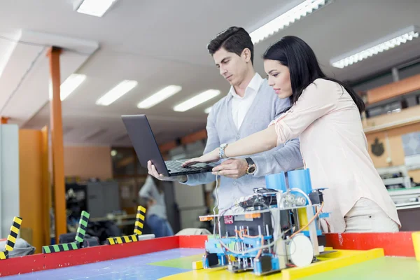 Dois estudantes inteligentes programando um robô — Fotografia de Stock