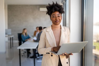 Modern bir şirket ofisinde çalışırken bilgisayar kullanan başarılı genç bir iş kadını.