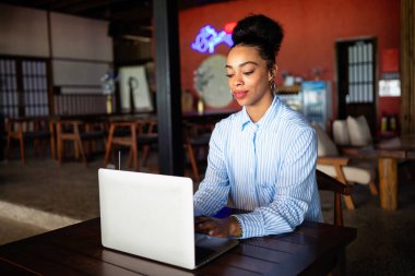 Happy freelancer enjoying a nutritious breakfast of smoothie and salad while using a laptop and working