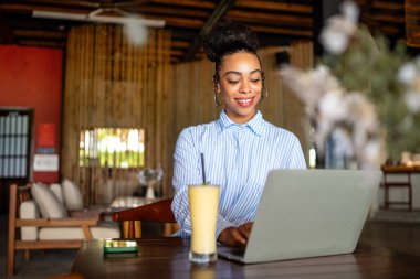 Happy freelancer enjoying a nutritious breakfast of smoothie and salad while using a laptop and working
