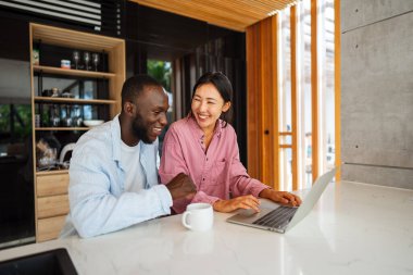 Uzaktan çalışan çok kültürlü bir çift, çevrimiçi finans ve yatırım planlıyorlar. Dijital göçebe yaşam tarzı, takım çalışması ve her yerden gelen akıllı finansal kararlar.