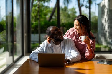 Genç mutlu çift evde dizüstü bilgisayar kullanırken eğleniyor. Dizüstü bilgisayarda yazarken kucaklaşan gençleri sevmek. Mutlu çift gelecek planlarını konuşuyor.