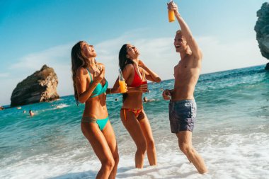 Group of young friends enjoying summer beach vacation with ocean waves, sunshine, and fun travel vibes on a tropical coastal destination
