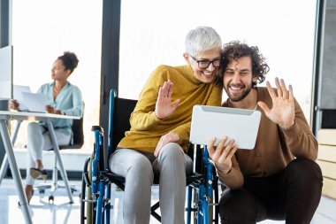 Tekerlekli sandalyedeki engelli kadın bilgisayara bakıyor, ırklar arası projeyi tartışıyor. Katılım, eşitlik mutlu iş insanları konsepti