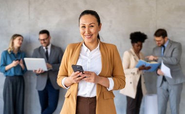 Ofisteki dijital cihazları kullanarak gülümseyen bir yönetici ekibi. Çeşitli profesyonel liderler yöneticiler ve çalışanlar takım çalışmasında çalışan dijital finans projesini tartışıyor.
