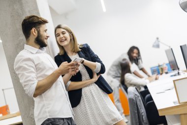 Telefonunu kullanarak ve gülümseyen iş arkadaşları