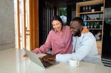 Genç mutlu çift evde dizüstü bilgisayar kullanırken eğleniyor. Dizüstü bilgisayarda yazarken kucaklaşan gençleri sevmek. Mutlu çift gelecek planlarını konuşuyor.