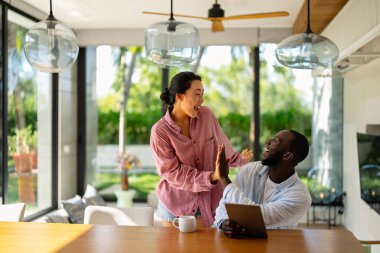 Genç ve çok ırklı çift evde bilgisayar ve dijital cihaz kullanırken eğleniyor. İnsanlar, teknoloji, online yaşam tarzı konsepti