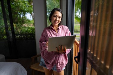 Orta Doğulu, Asyalı bir kadın internet bankacılığını, sosyal hayatını ve rahat, modern bir ev ortamında dizüstü bilgisayardaki görevlerini yönetiyor.