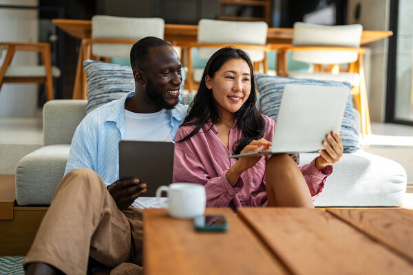 Мультикультурная пара работает удаленно, планируя финансы и инвестиции в Интернете. Цифровой кочевой образ жизни, командная работа и умные финансовые решения откуда угодно