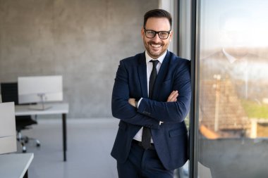 Yakışıklı, başarılı bir iş adamı ekibinin önünde şirket ofisinde kendinden emin duruyor.