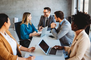 Tam konsantrasyon. Takım olarak çalışan ve kurumsal ofiste iletişim kuran bir grup genç iş adamı.