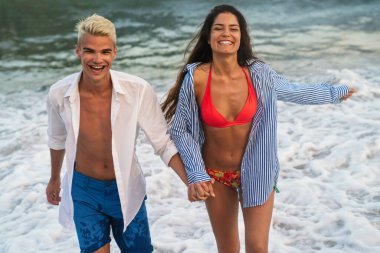 Genç çift denizde evlendikten sonra balayının tadını çıkarıyor. Mutlu sıradan bir çift el ele tutuşup sahilde yürüyor.