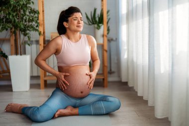 Hamile kadın kasılmalar hissediyor. Acısını dindirmeye çalışıyor. Acının gelmesini bekliyor..
