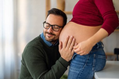 Aşk, şefkat, ilişki ve yeni aile kavramı. Aşık bir adam hamile karısına sarılır, birlikte bebeklerin gelmesini beklerler.