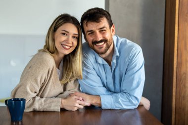 Mutlu ve çeşitli çiftler evlerinde neşeli bir anı paylaşıyorlar. Sıcak, modern bir iç mekanda kucaklaşıp gülümsüyorlar. Aşkı, birlikteliği ve gerçek bağlantıyı kutluyorlar.