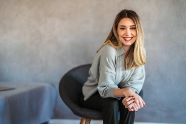 Modern bir iç mekanda gülümseyen, kendine güvenen beyaz bir iş kadını, temiz, şık bir portre ortamında liderlik, profesyonellik ve başarı sergiliyor.