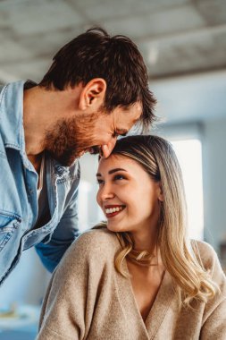 Mutlu çift sıcak bir şekilde gülümsüyor, evde sevgi, destek ve karşılıklı saygıyla dolu olumlu bir ilişkiye duygusal denge ve güven gösteriyor.