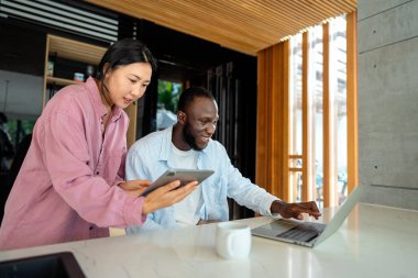 Evde dizüstü bilgisayarlı, yatırım, tasarruf ve faturalar için bütçe planlayan çok ırklı mutlu çift. Çevrimiçi bankacılık ve çeşitli, çok ırklı karı ve kocalarla finansal ödeme