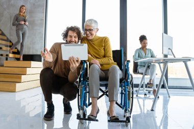 Farklı profesyonellerden oluşan bir grubun birlikte çalıştığı parlak, çağdaş bir ofis. Tekerlekli sandalye kullanan birini de kapsar.