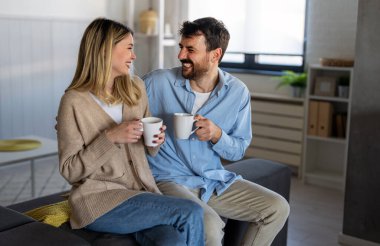 Sevgi dolu bir çift, evde sakin bir sabahta kahveyle eğleniyor, gülümsüyor ve birlikte huzurlu bir anı paylaşıyor. Sıcaklık, uyum ve günlük mutlulukla dolu.