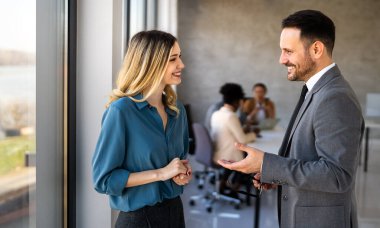İki farklı etnik çeşitlilikte mutlu iş adamı şirket ofisinde dizüstü bilgisayar kullanarak konuşuyorlar. İş yerindeki meşgul iş adamları ve kadın meslektaşları.