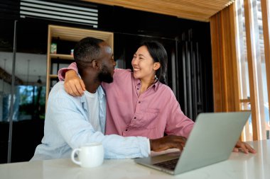 Başarılı çeşitlilik, çok ırklı bağımsız çift, birlikte dizüstü bilgisayarda çalışarak, tropik iklimin huzurlu ortamının tadını çıkarıyor..
