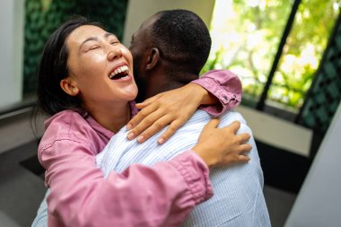 Mutlu ve çeşitli çiftler evlerinde neşeli bir anı paylaşıyorlar. Sıcak, modern bir iç mekanda kucaklaşıp gülümsüyorlar. Aşkı, birlikteliği ve gerçek bağlantıyı kutluyorlar.