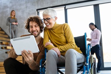 Tekerlekli sandalyedeki kadına yardım etmek, modern ofiste sohbet etmek. Takım çalışması, işyeri, iş dünyası, çeşitlilik, işbirliği, destek