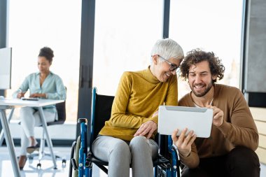 Modern bir çalışma alanında işbirliği yapan, çizelgeleri analiz eden ve birlikte çalışan çok ırklı iş arkadaşları, takım çalışmalarını, çeşitliliği ve dahil edilmeyi gösteriyor