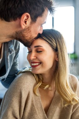 Yeni evlerinde mutlu bir çift, birlikte yeni bir bölüme başlarken gülümsüyor ve kucaklaşıyorlar, aşkı, ortak geleceği ve birlikte yaşamanın heyecanını simgeliyorlar.