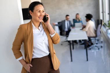 Modern bir ofiste, başarılı bir iş kadını telefon iletişimi, liderlik, strateji ve mesleki hırsını gösteren birden fazla iş yapar.