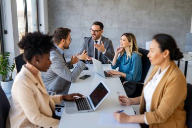 İş projesi ekibi şirket ofisindeki toplantı odasında birlikte çalışıyor.