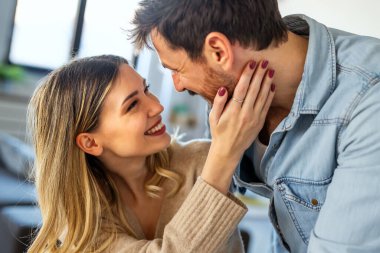 Romantik çift gülümsüyor ve evlerinde samimi bir anı paylaşıyor, gerçek duygularla sevgi, güven ve mutluluğu ifade ediyorlar ve sıcak bir sevgi bağı kuruyorlar.