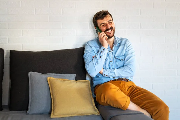 Kapalı alandaki bir telefon görüşmesi sırasında gülümseyen bir adam, dostça ilişkiler, neşeli sohbetler ve günlük insan etkileşiminin sıcaklığıyla dolu canlı bir sosyal an yakalar.