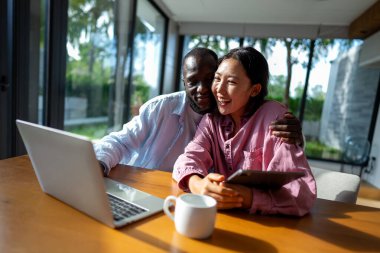 Genç mutlu çift evde dizüstü bilgisayar kullanırken eğleniyor. Dizüstü bilgisayarda yazarken kucaklaşan gençleri sevmek. Mutlu çift gelecek planlarını konuşuyor.