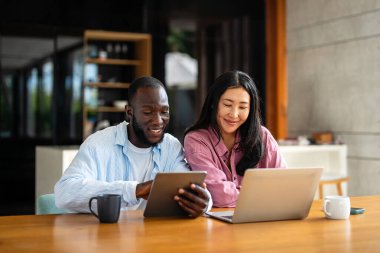 İş ekibi, iki mutlu çeşitlilik, çok ırklı yönetici ofiste dizüstü bilgisayar kullanarak birlikte çalışıyorlar. Genç iş kadını yöneticisi iş toplantısında sunum yapıyor, danışmanlık yapıyor.