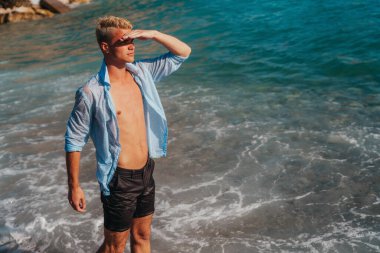 Kaygısız genç adam deniz kenarında tatilin tadını çıkarıyor, özgürlüğü, rahatlığı, mutluluğu ve tatilde yaşamanın saf neşesini kutluyor.