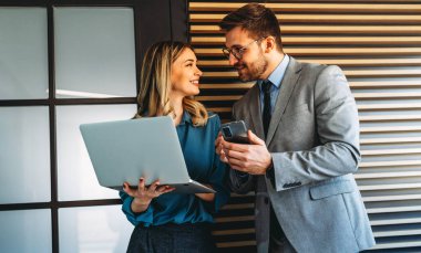Ofisteki dijital cihazları kullanarak gülümseyen bir yönetici ekibi. Çeşitli profesyonel liderler yöneticiler ve çalışanlar takım çalışmasında çalışan dijital finans projesini tartışıyor.