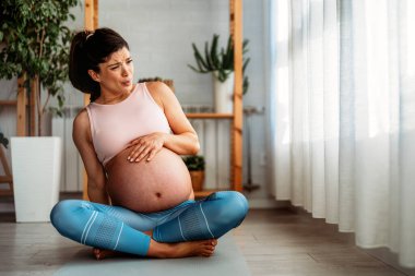 Hamile kadın kasılmalar hissediyor. Acısını dindirmeye çalışıyor. Acının gelmesini bekliyor..