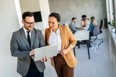 Mixed team of software engineers brainstorming ideas for new code library in front of computer screens compiling algorithms. Diverse app developers collaborating on group project in it agency office.