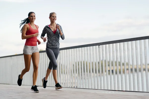 Två sportiga kvinnor jogging i city — Stockfoto