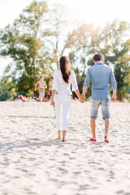 Kumsalda yürüyen bir çift.